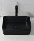 Black ceramic rectangular vessel sink with faucet and drain, contrasting on white counter, modern design for bathrooms