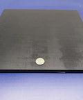 UHMW PE Black Sheets Set Of Two Three Eighths Inch Thick Twelve By Twelve Inches Durable Wear Resistant Workhorse Surface With Serious Impact Strength Meets ASTM D 4020 05 Compliance. Square black sheet with coin for scale on blue background.