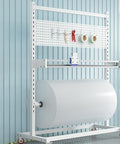 Heavy Duty Fabric Roll Storage Rack With Adjustable Cutter And Rock Solid Base For Quick Material Trim And No Sweat Packing Operations In Any Workshop Or Industrial Setting, featuring a large white paper roll.