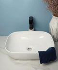 USZWBY Vessel Sinks Square Rounded Corner Simple Sink Ceramic Above Counter Wash Basin with navy towel and faucet.