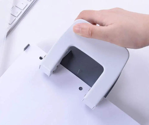 Hand using Two Hole Puncher For Paper And Crafts, Adjustable 3.15 Inch Hole Spacing, Squeeze To Punch Up To 20 Sheets, White Finish.