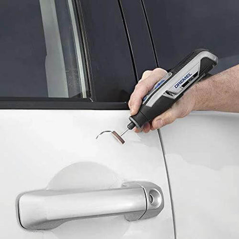 Dremel cordless rotary tool in hand, engraving near a car door handle.