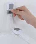 Hand using Upgraded No Drill Furniture Wall Anchors For Baby Proofing And Child Safety, 4 Pack Cabinet Strap Locks on white surface.