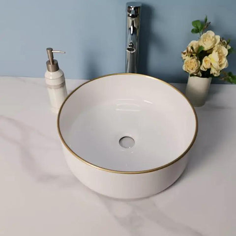 USZWBY Vessel Sinks Simple Hotel Bathroom Ceramic Sink Home Round Above Table Basin with gold rim and modern faucet.