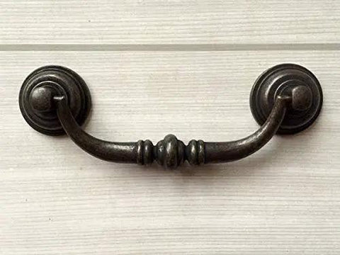 Vintage Look Bail Drawer Pulls Drop Handles 4.25 Inch Center-To-Center Dark Antique Bronze Cabinet Hardware mounted on wood.