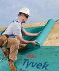 Worker applying Zero Hassle Heavy Duty Synthetic Roof Underlayment Covers A Whole 10 Squares Of Your Deck Pro Level waterproof protector.