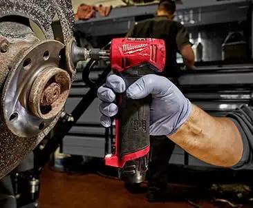 Top Shelf Brushless Right Angle Die Grinder 12V Cordless Powerhouse, handheld, working on a rusted brake component in a garage.