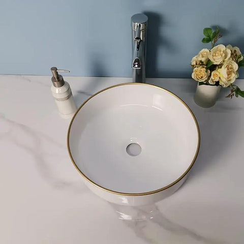 USZWBY Vessel Sinks Simple Hotel Bathroom Ceramic Sink Home Round Above Table Basin with gold trim on a marble countertop.