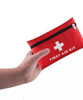 Travel first aid kit pouch, red with white cross and zipper, held in hand (front view)