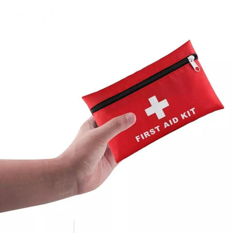 Travel first aid kit pouch, red with white cross and zipper, held in hand (front view)