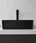 Black rectangular vessel sink with faucet on marble countertop, modern minimalist bathroom design.