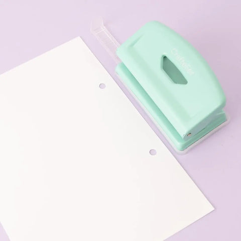 Mint finish 2 Hole Puncher With Waste Tray, 10 Sheet Capacity, by a sheet with punched holes, highlighting adjustable guide and non-slip base.