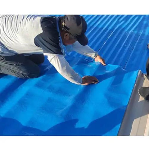 Tough As Nails Waterproof Roof Repair Tape Roll being applied on a blue roof surface by a worker.
