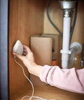 Hand installing Flo Smart Water Leak Detector 3 Pack under sink for real time alerts and round the clock leak monitoring.