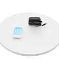 Heavy Duty Motorized Rotating Display Stand With Smooth 360 Degree Turntable For Product Photography And Retail Exhibits Supports Up To 220lbs Loads on a white turntable with remote and power adapter.