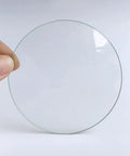 Person holding a piece of the Lab Watch Glass Set With Beaker Cover Lids, 3.9 Inch Diameter, 12 Pieces, Thickened High Transparency Glassware