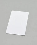 Plug And Play Blank PVC Cards For ID And Business Badges Waterproof Stock No Chip Universal Fit smooth white PVC card on gray background.