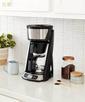 Heat N Brew 10 Cup Programmable Coffee Maker with stainless steel finish on kitchen counter with coffee essentials