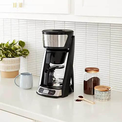 Heat N Brew 10 Cup Programmable Coffee Maker with stainless steel finish on kitchen counter with coffee essentials