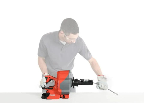 User operating a Heavy Duty Cordless Drain Snake With Brushless Motor and twenty five foot steel cable for drain clearing.
