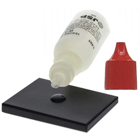 Waytest 18K gold testing solution bottle with red cap and dropper over black testing tile