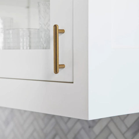 Close-up of Six Pack 3-Inch Classic Curvature Cabinet Handles in Antique Brass on a kitchen cabinet door.