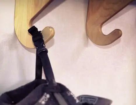 Premium Wall Rack Mount For Ski Snowboard And Longboard Storage Featuring Adjustable Baltic Birch Arms Heavy Duty Gear Holder Holds Up To One Hundred Twenty Pounds with straps hanging.