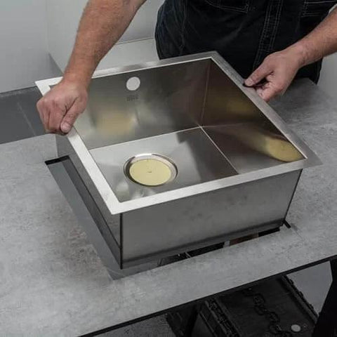 Person installing a stainless steel sink into a countertop