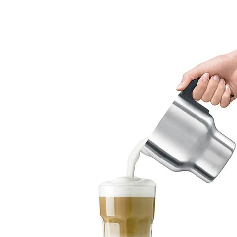 Hand pouring milk from Milk Café Frother With Induction Heating Delivers Rich Creamy Foam For Lattes And Cappuccinos into glass mug