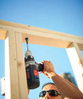 Blue cordless drill drilling into a wooden frame outdoors