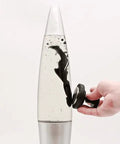 Decorative Retro Rocket Ship Ferrofluid Lava Lamp with Magnetic Black Wax in Clear Liquid, silver base, hand holding magnet influence.