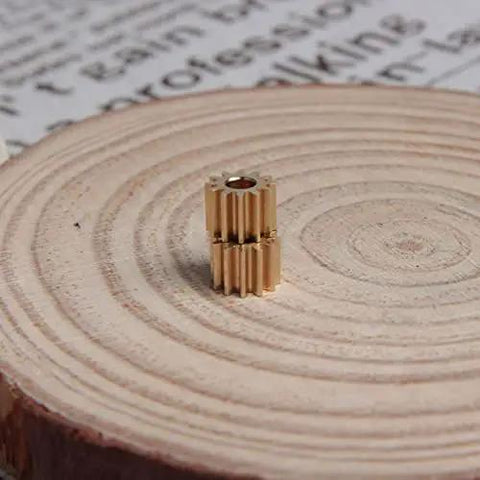 Two Pack Brass Spur Gears, 0.5 Modulus, 12 Teeth, 3mm Bore, 5mm Gear Width, shown on wooden disc.