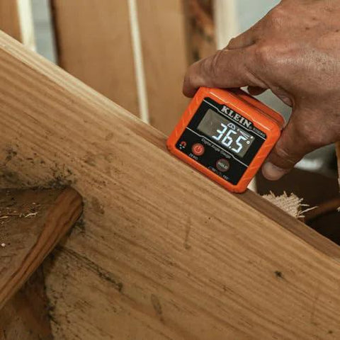 Klein Tools 935DAG digital level in orange held against wood; display reads 36.5°.