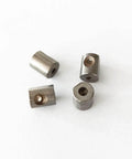 Waterjet mixing chamber bushings, four metal cylindrical spacers with central bores.