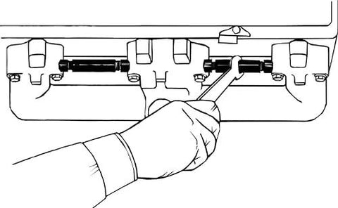Exhaust manifold spreader installed between small-block Chevy exhaust manifolds; handheld tool.