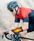 Cyclist wearing wrist heating pad for pain relief, featuring Cordless Wrist Hand Heating Pad Massage For Carpal Tunnel Relief With 3000mAh Battery And Vibration.