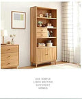 Wooden shelving unit with drawers and decor beside a light-filled window in a minimalist room.