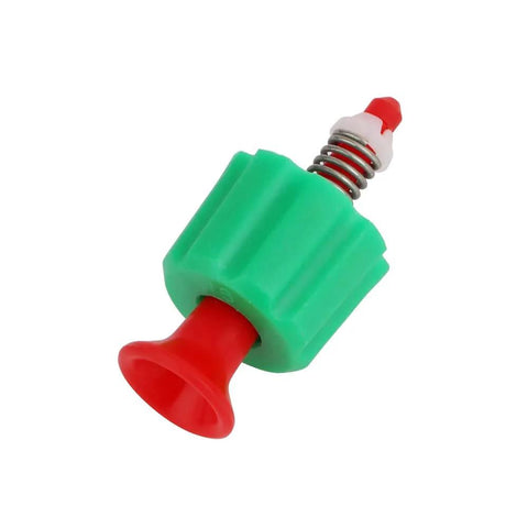 Close-up of a pressure relief valve for garden backpack sprayer; green plastic body, red nozzle, and metal spring.