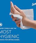 Close-up of a hand pulling a white Scott Professional universal multifold paper towel on blue background