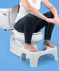 Front view of Squatty Potty Simple Curve 7-inch white toilet stool with user resting feet on it.