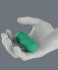 White hand holding a green tool, possibly for therapeutic use, highlighting ergonomic design and compact size.