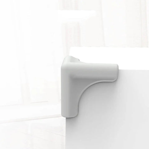 Gray silicone corner protector attached to table edge, part of 4 Pack Silicone Corner Protectors For Furniture And Walls Soft Yet Durable Edge