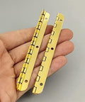 Two Pack Golden Metal Hinges For Cabinets And Furniture Hardware held in hand, showcasing antique vintage look for DIY repairs.