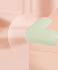 Light green PVC Night Light Corner Guard on furniture edge, L shaped protector for baby proofing dining tables and study desks.