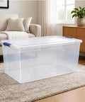Heavy Duty 105 Quart Storage Bin With Secure Snap Latches And Clear Base in a living room setting with soft natural light.