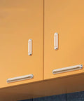 Eight clear silicone cabinet bumpers with adhesive installed on orange cabinet doors and drawers