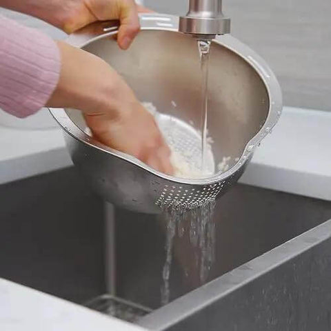 Person using Stainless Steel Rice Washer Strainer Bowl With Agitator Bumps For Quick No Fuss Rinsing in kitchen sink