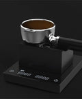 Solid Kickass Coffee Tamping Station With Integrated Espresso Scale Base with portafilter on black surface.