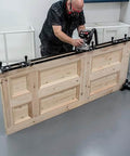 Person using All-In-One Adjustable Door Hinge Jig Installation Kit For 2 Ft 6 In To 9 Ft Doors with router on wooden door.