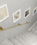 Hella Sturdy Gold Wrought Iron Handrail For Elderly And Kids Safety Stair Railing mounted on a staircase wall with framed art.